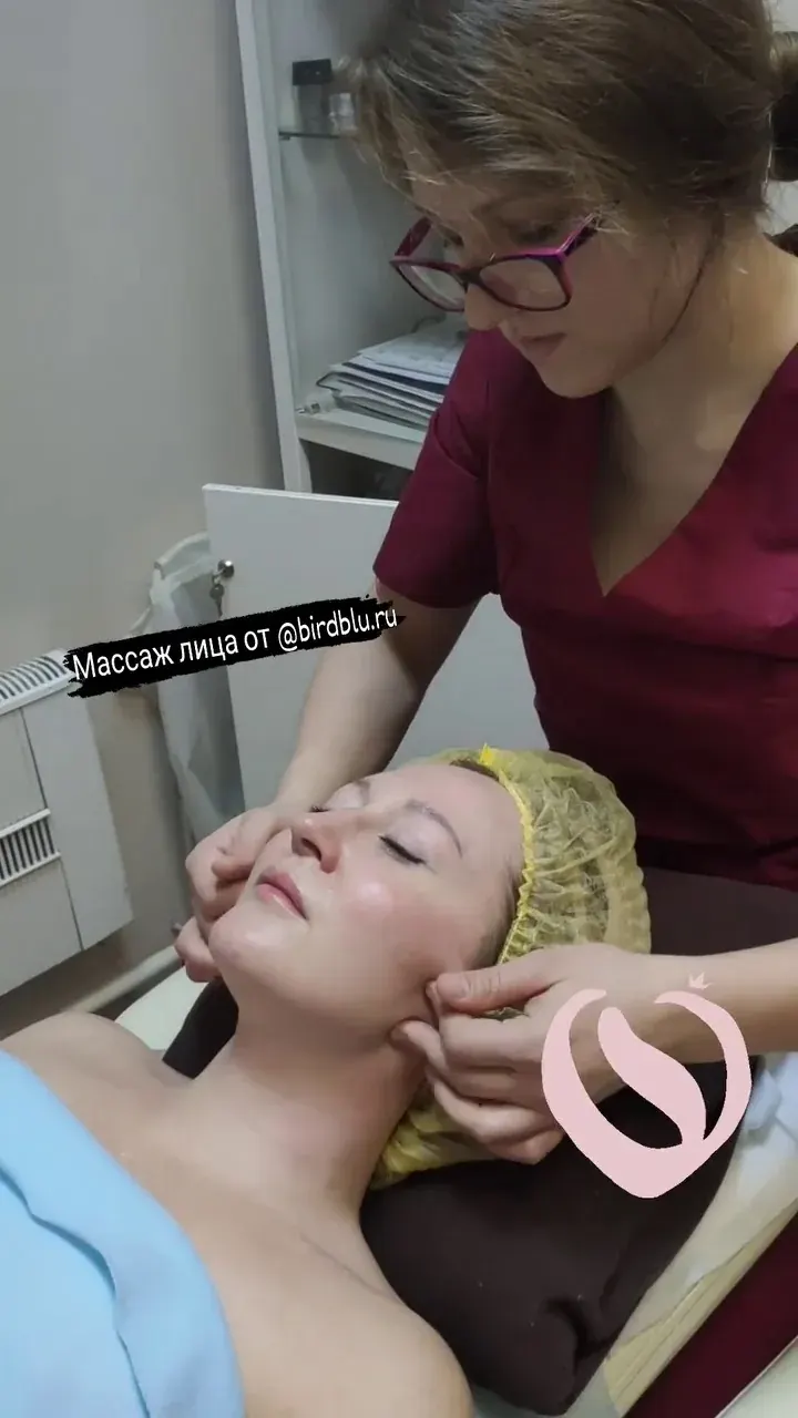 Женщина проходит массаж лица и шеи у специалиста в клинике «Синяя Птица Женщина проходит массаж лица и шеи у специалиста в клинике «Синяя Птица