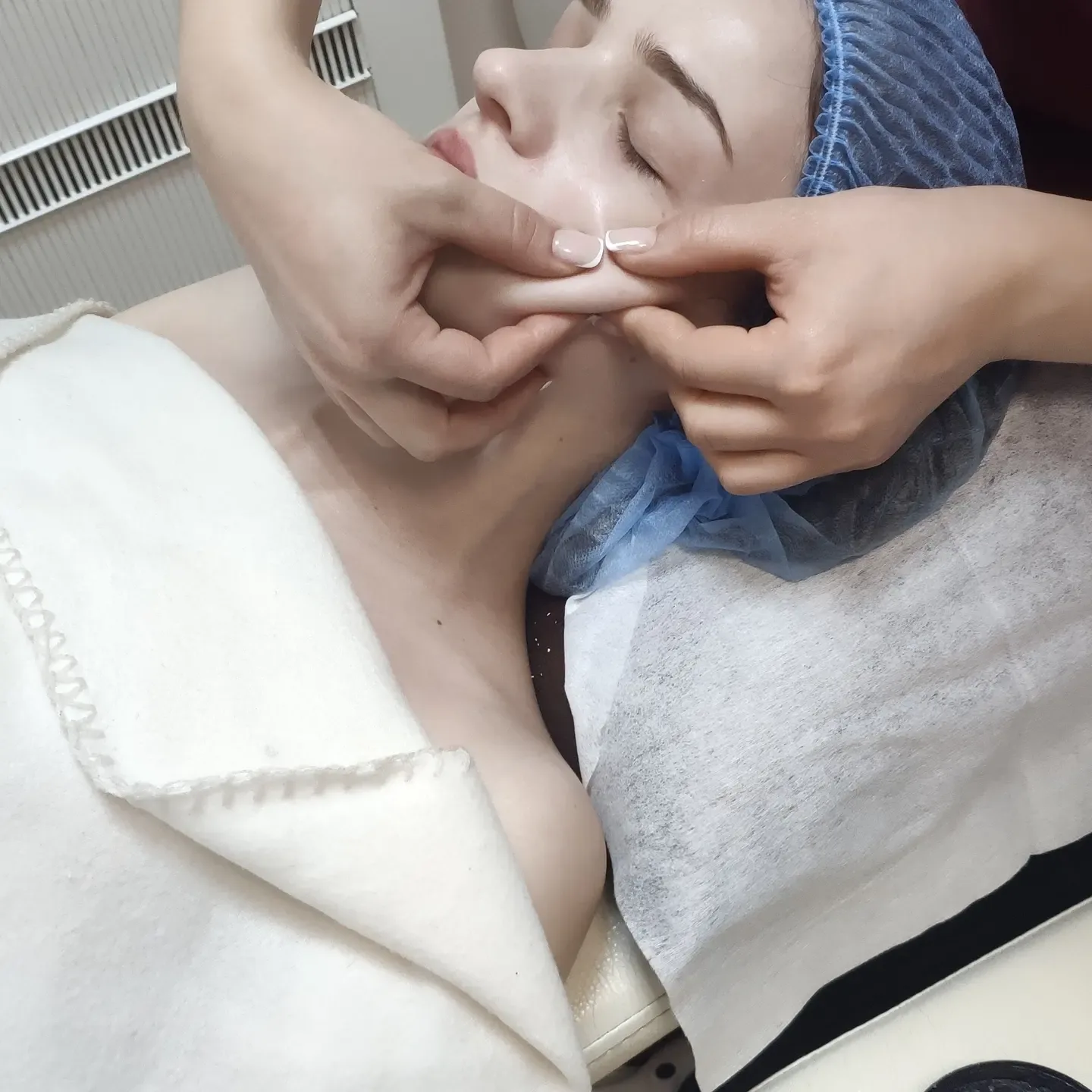 Крупный план процедуры ухода за кожей лица в салоне, мастер пальцами обрабатывает зону вокруг рта
