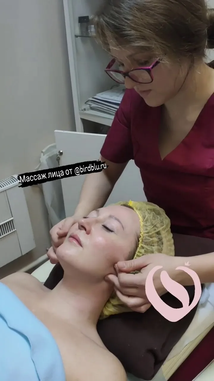 Женщина получает массаж лица и шеи в клинике, специалист в медицинской форме проводит процедуру